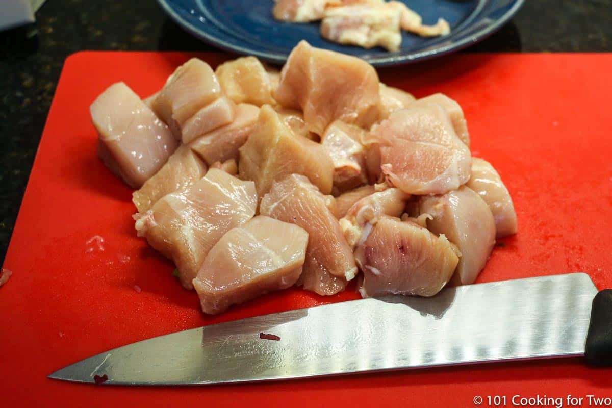 trimmed chicken on red board.