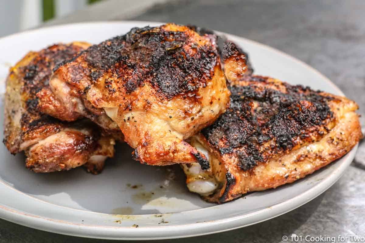 un plato gris lleno de muslos de pollo a la parrilla