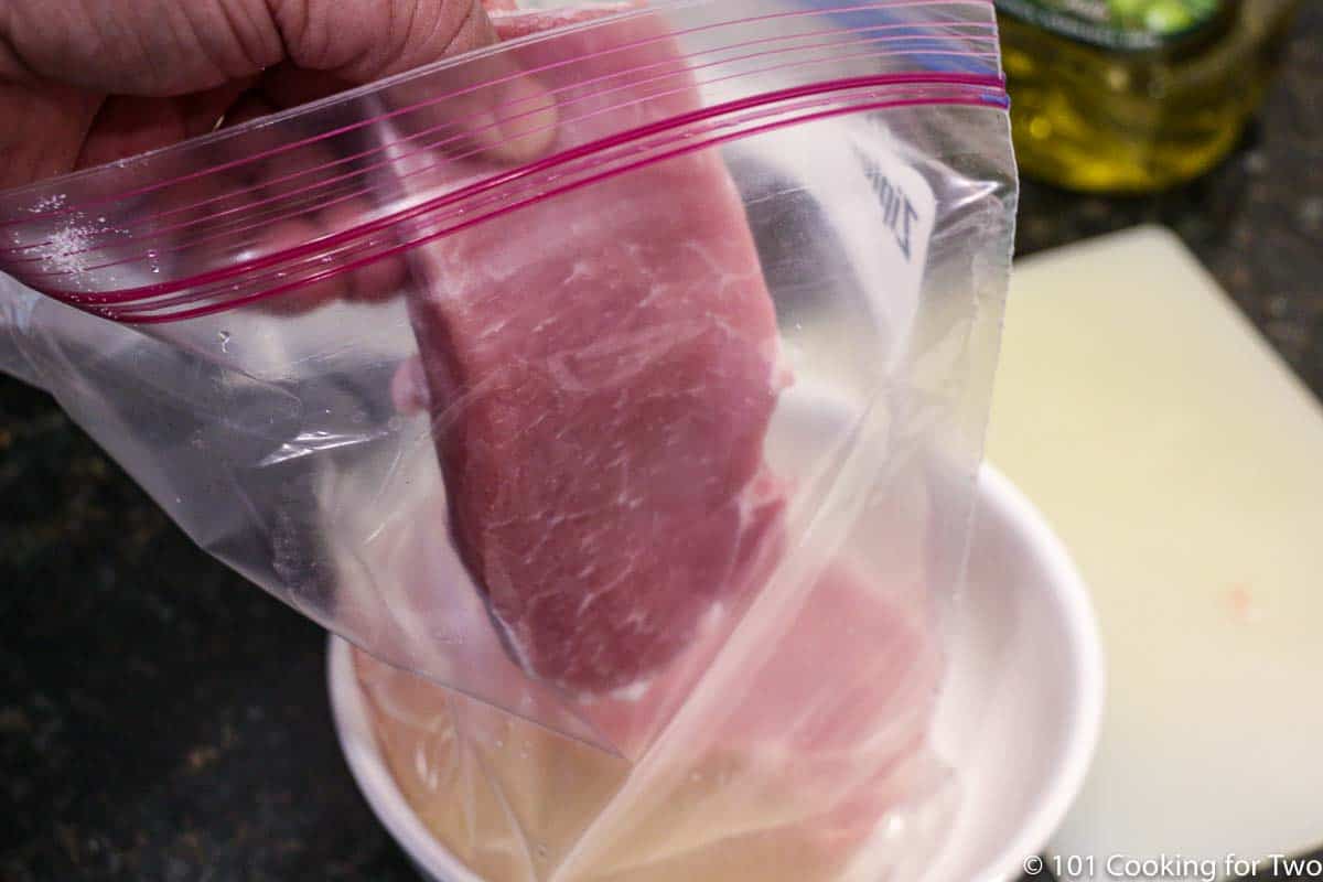 adding a pork chop to a bag of brine