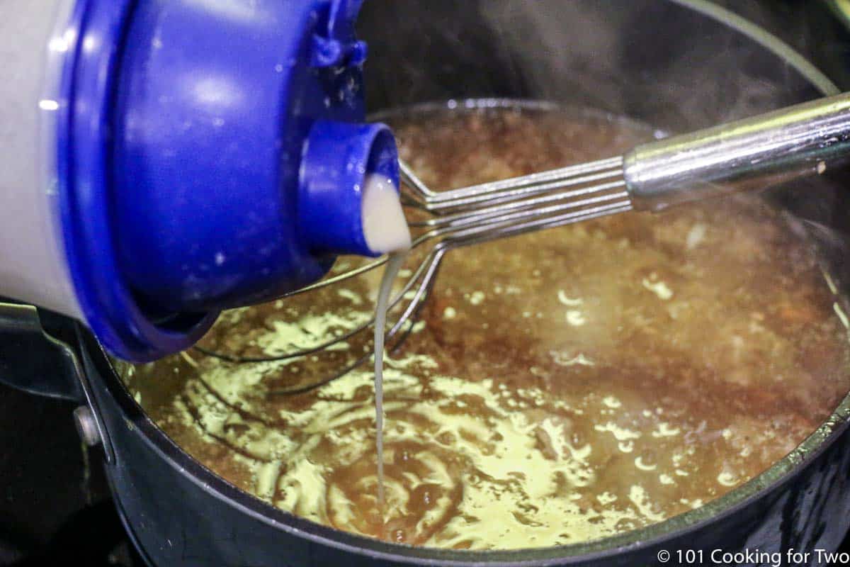 adding flour mixture to boiling fluid in saucepan.