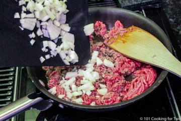 adding onion to burger in pan
