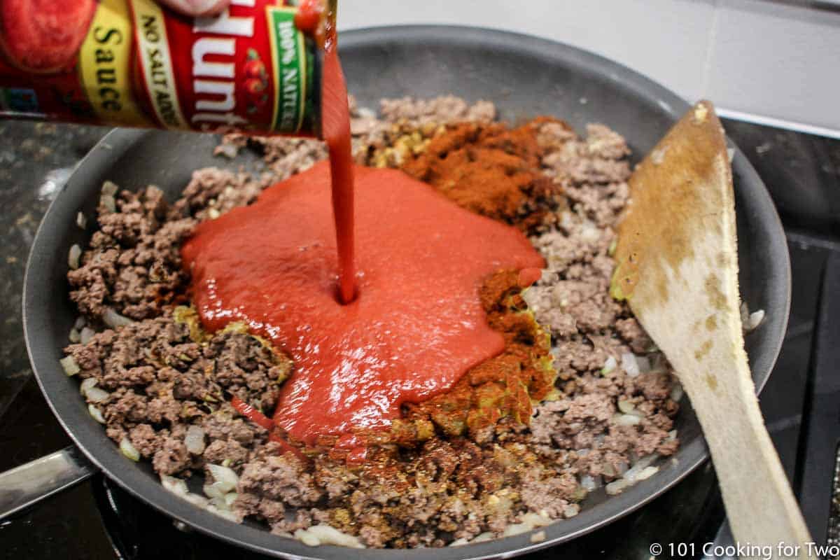 adding tomato sauce to cooked burger