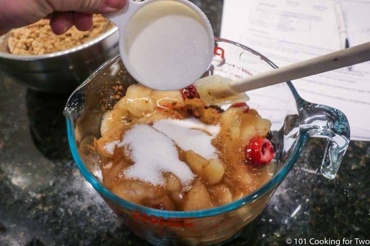 adding sugar to fruit in bowl
