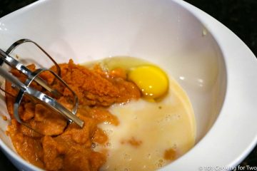 beating pumpkin and egg in white bowl