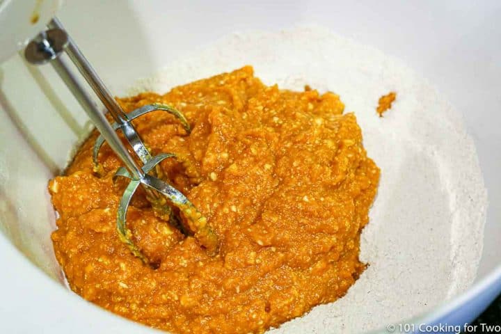 breating the pumpkin mixture into the dry in a white bowl