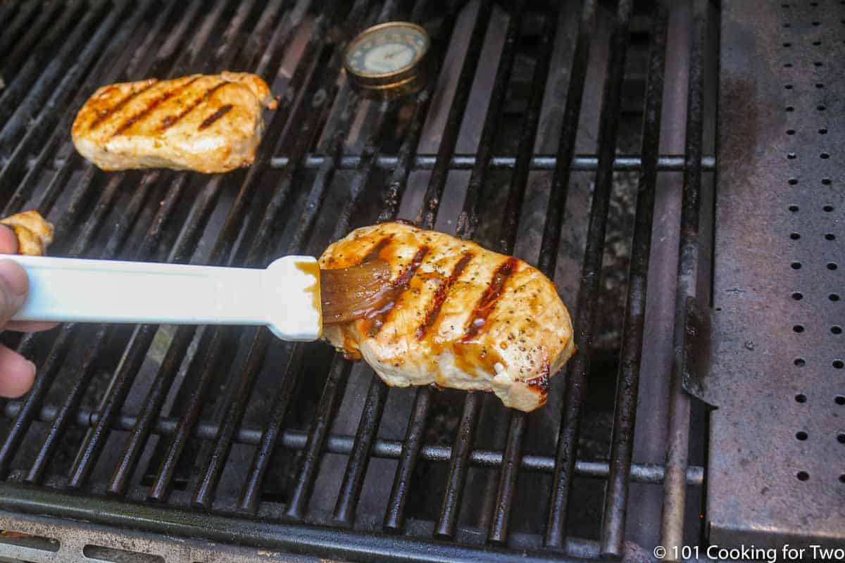 brushing pork chops with more glaze while on the grill