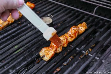 brushing the chicken kabob with BBQ sauce