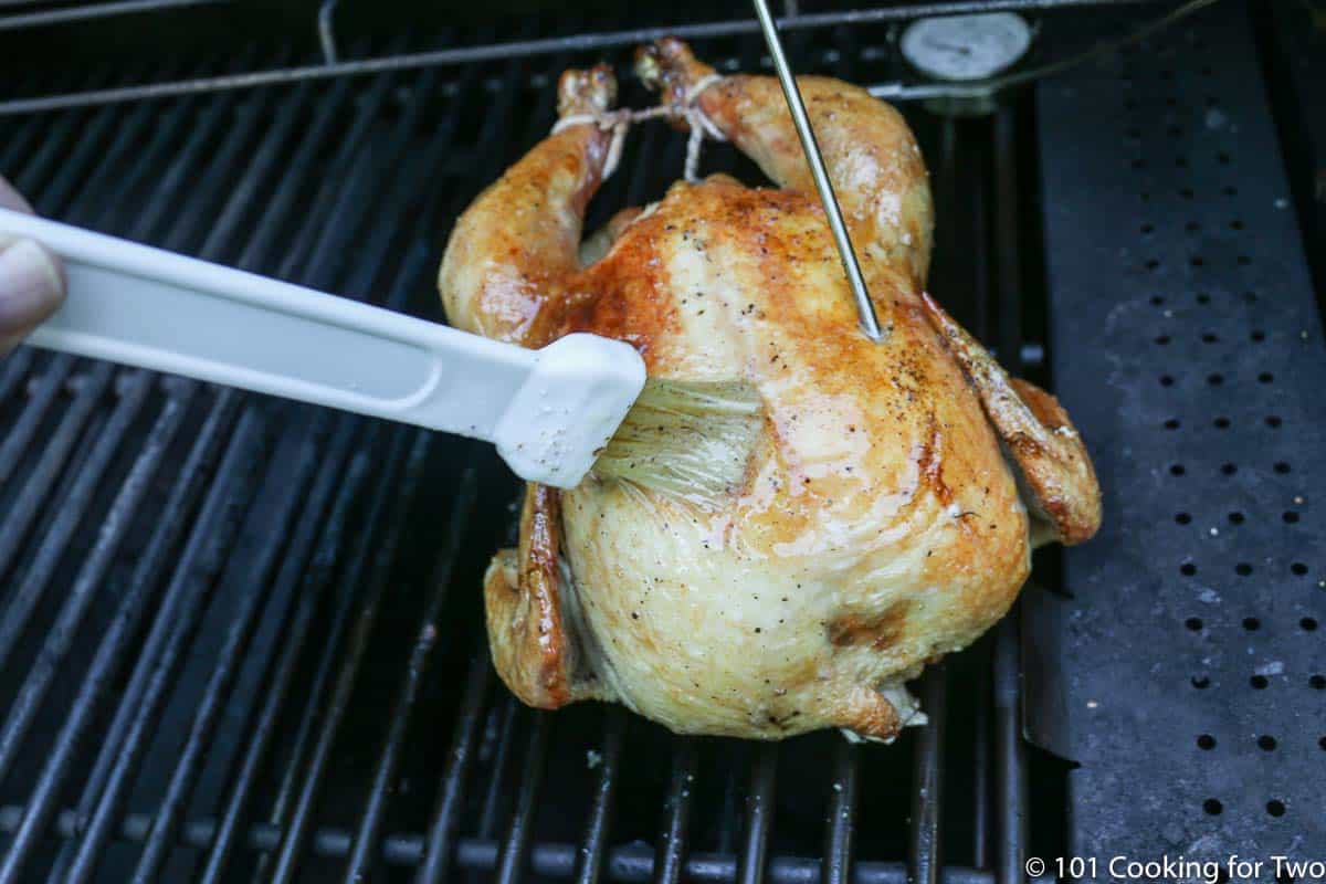 brushing the chicken on the grill after rotation.