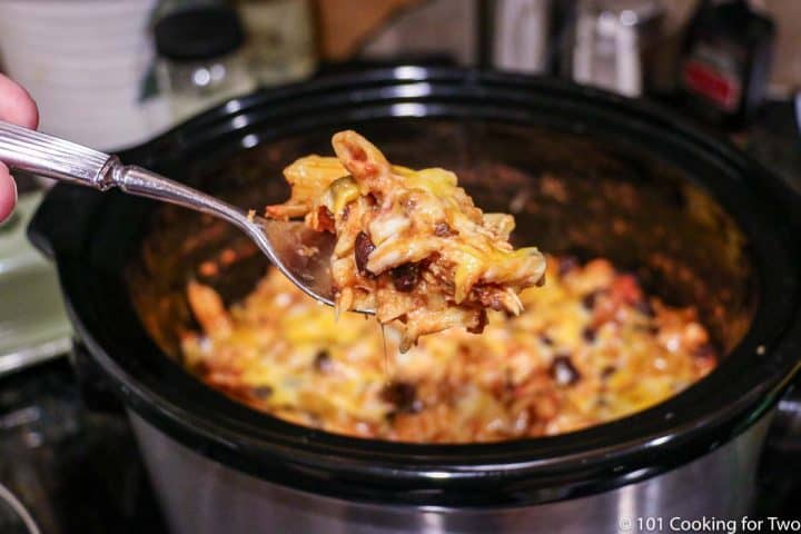 cheesy chicken casserole on a large spoon over the crock pot
