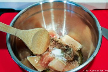 mixing chicken with spices in metal bowl