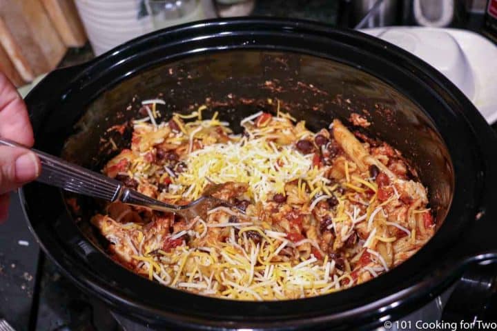 mixing shredded chicken and cheese into crock pot