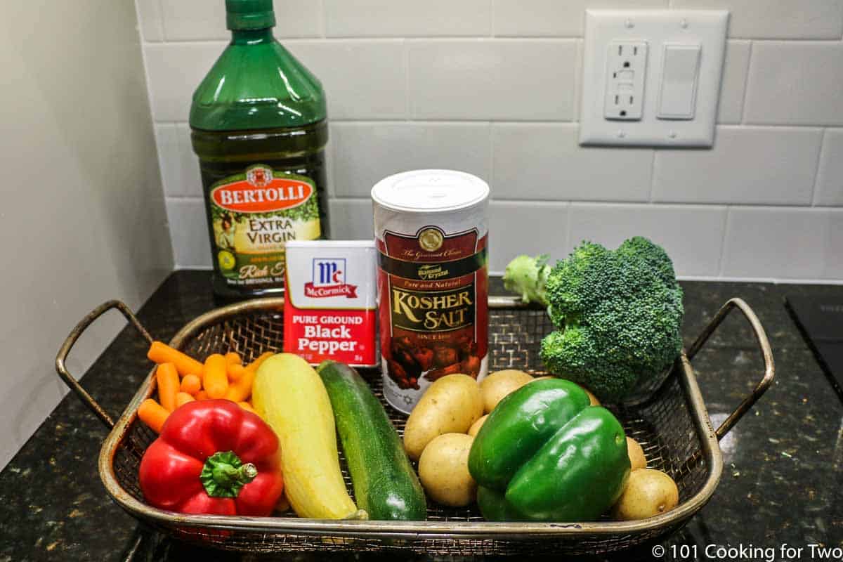 multiple raw vegetables in a grill pan with salt pepper and oil