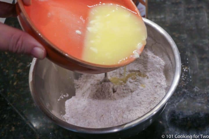 pouring melted butter into bowl with topping