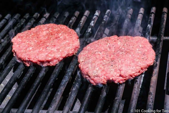 raw burger on the grill with a bit of smoke