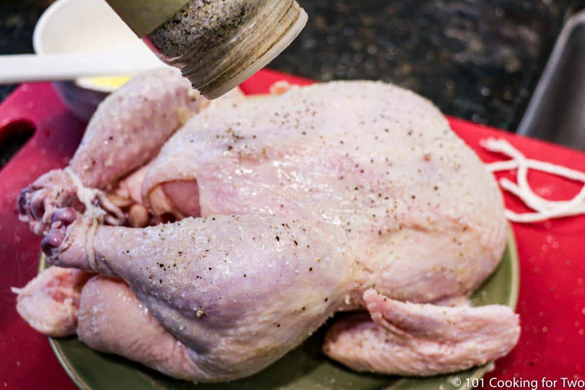 shaking seasoning on the chicken.