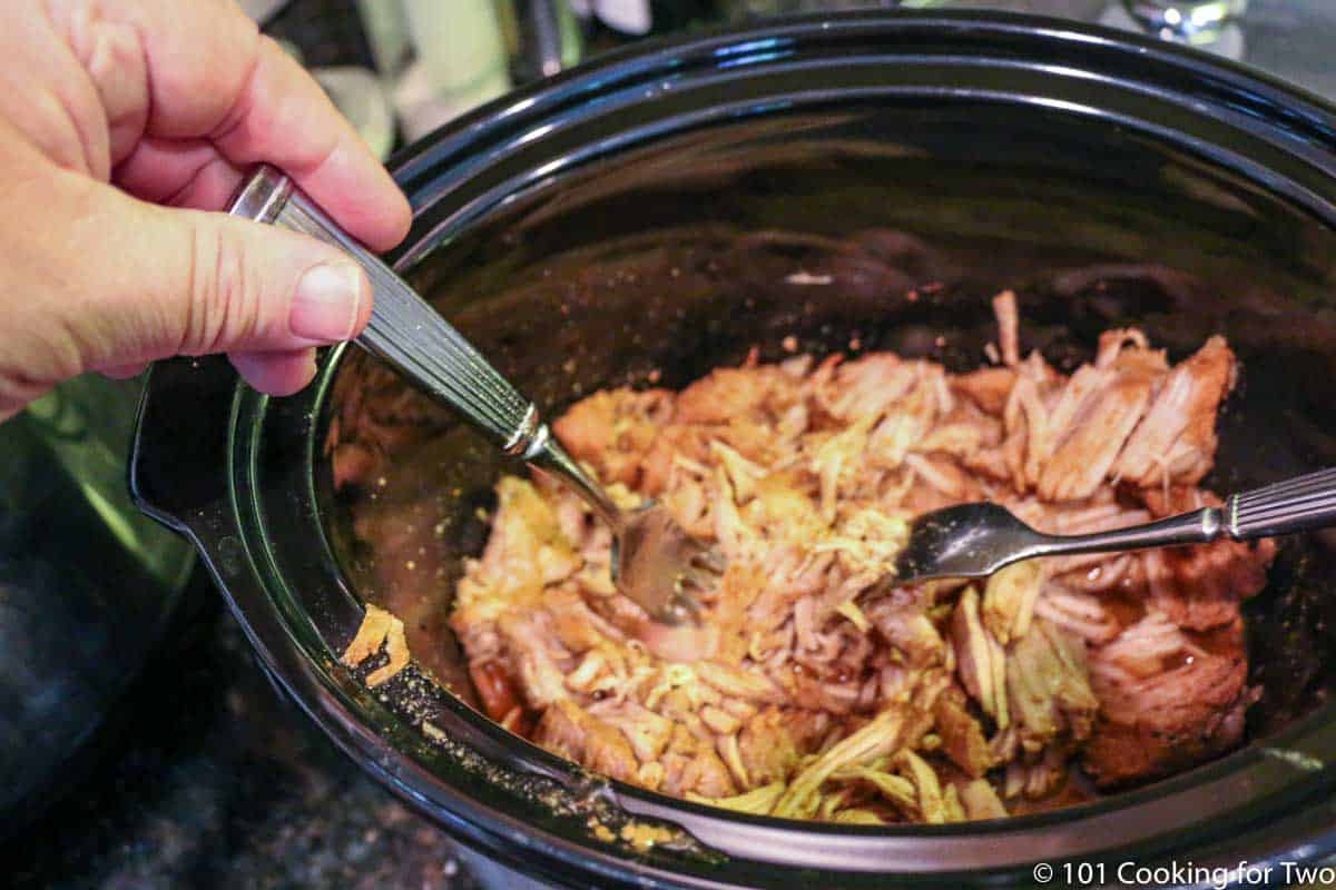 shredding the cooked pork tenderloin in the crock pot