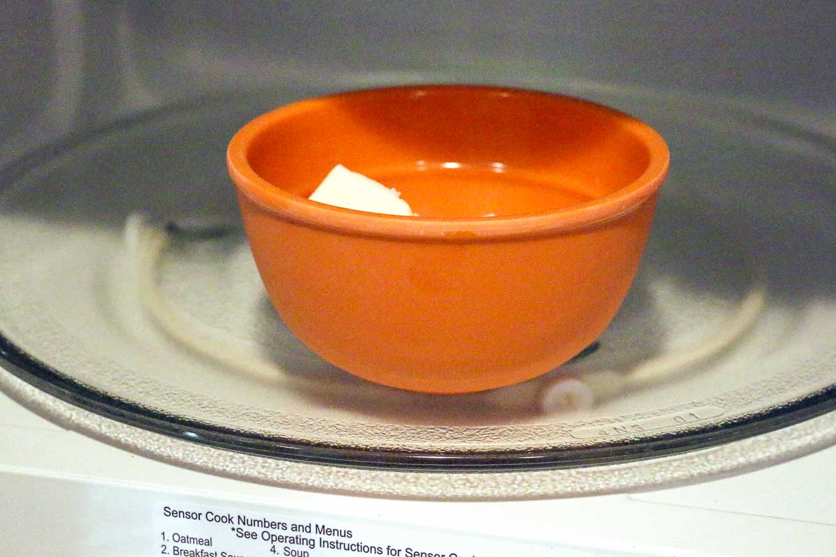 small orange bowl with butter in a microwave