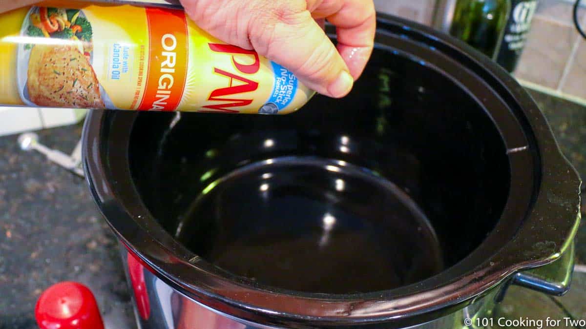 spraying a crock pot with PAM.