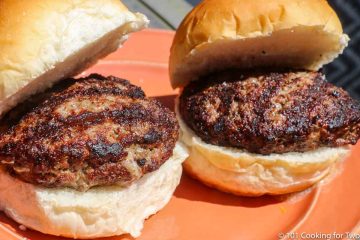 two cooked burgers on buns and orange plate