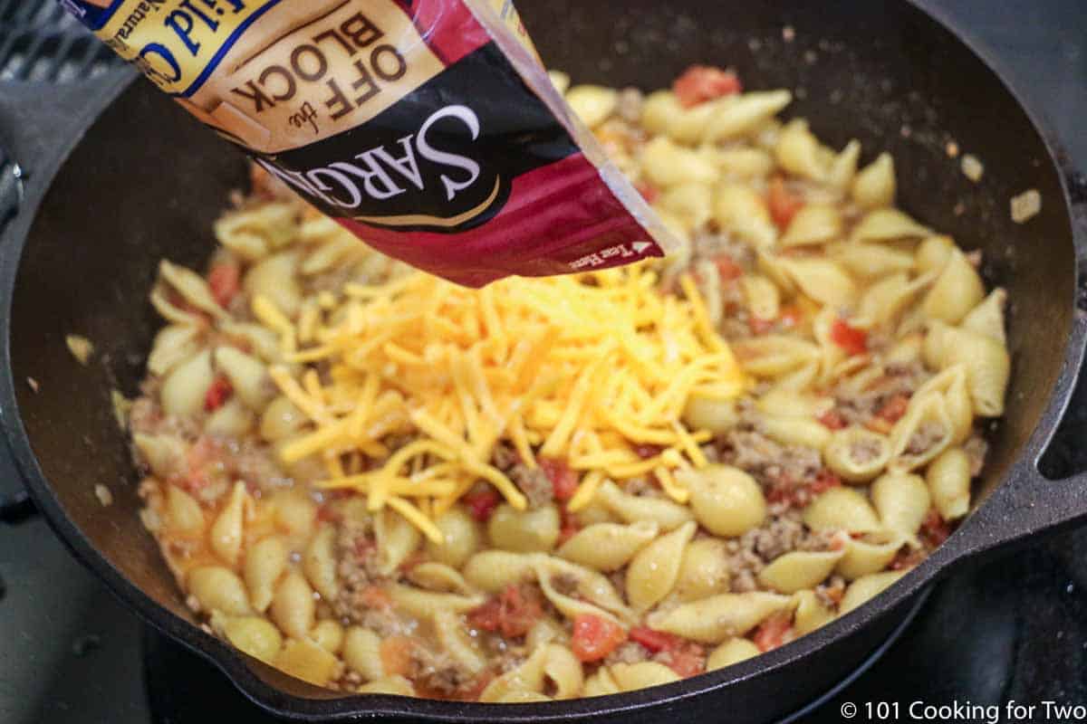 adding cheese to cooked chili mac