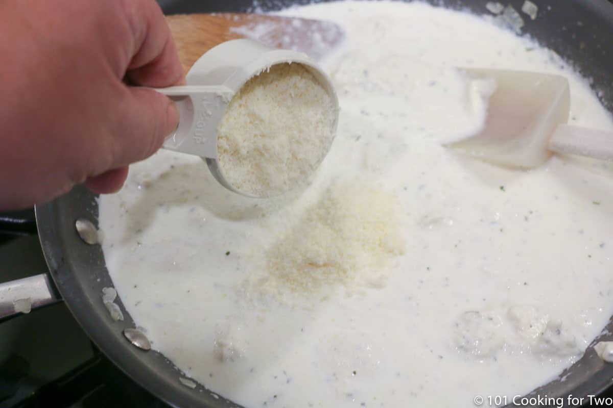 adding cheese to sauce in pan.