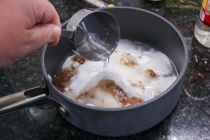 adding corn syrup into a sauce pan with sugar