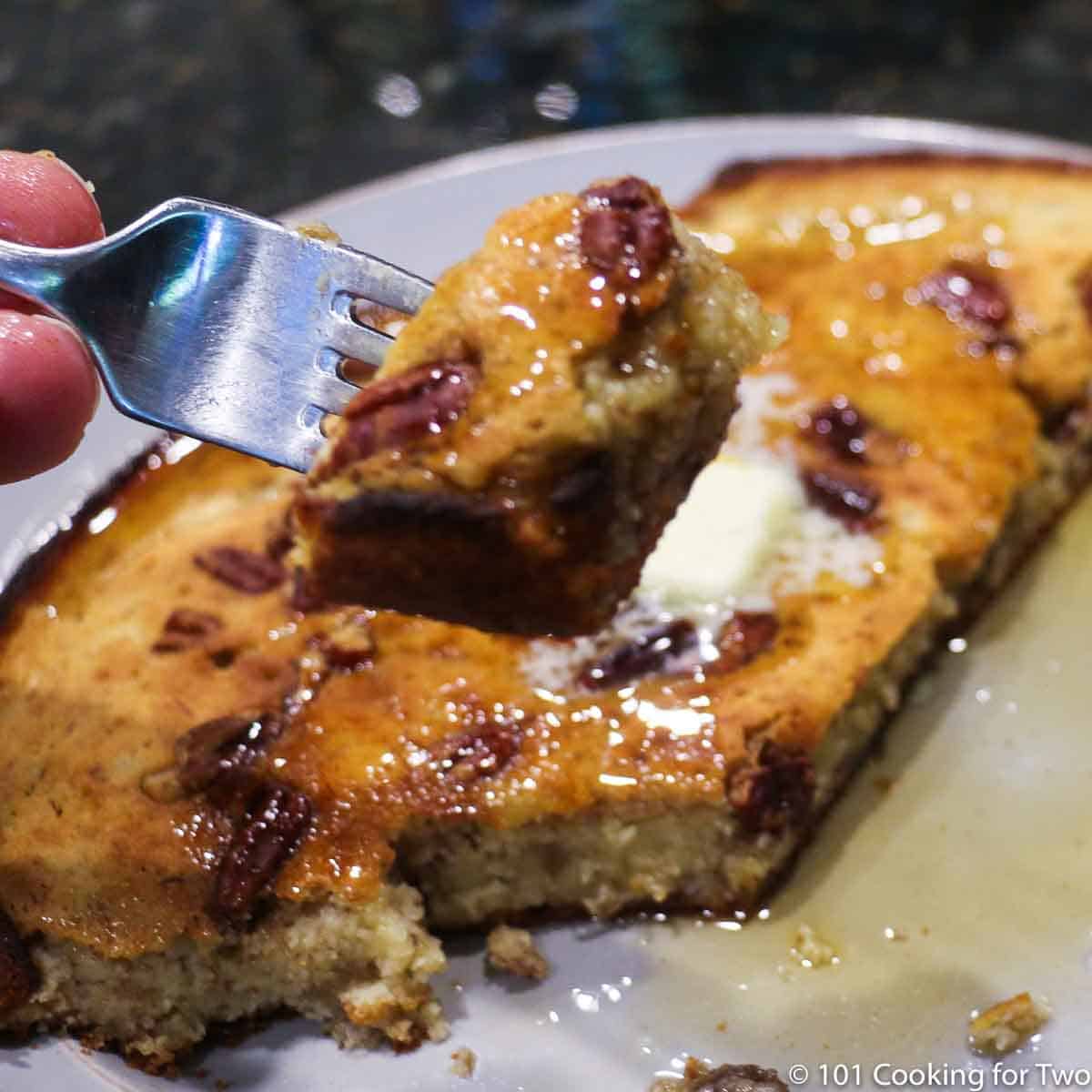 bite of pancake on a fork with syrup and nuts.