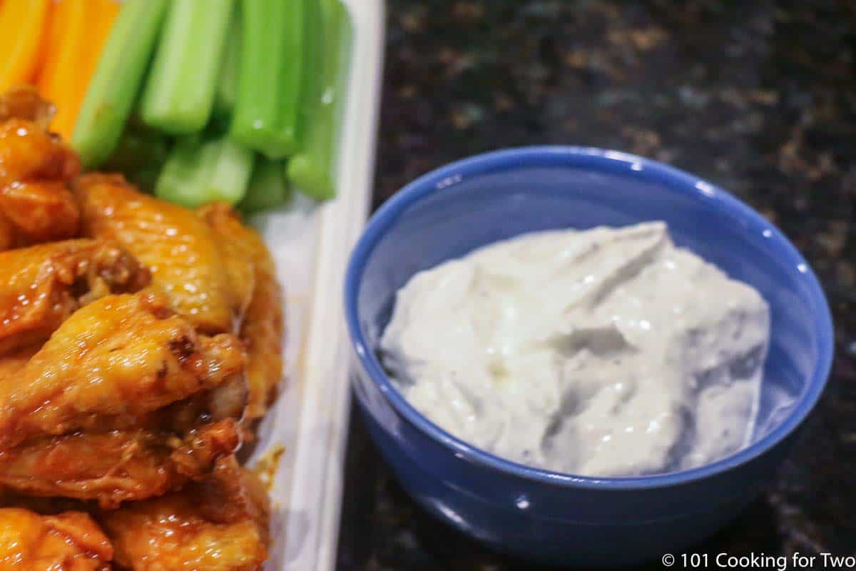 blue bowl of dip next to wings.