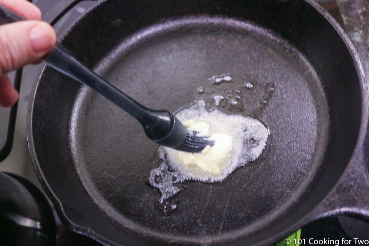 coating pan with melting butter with brush.