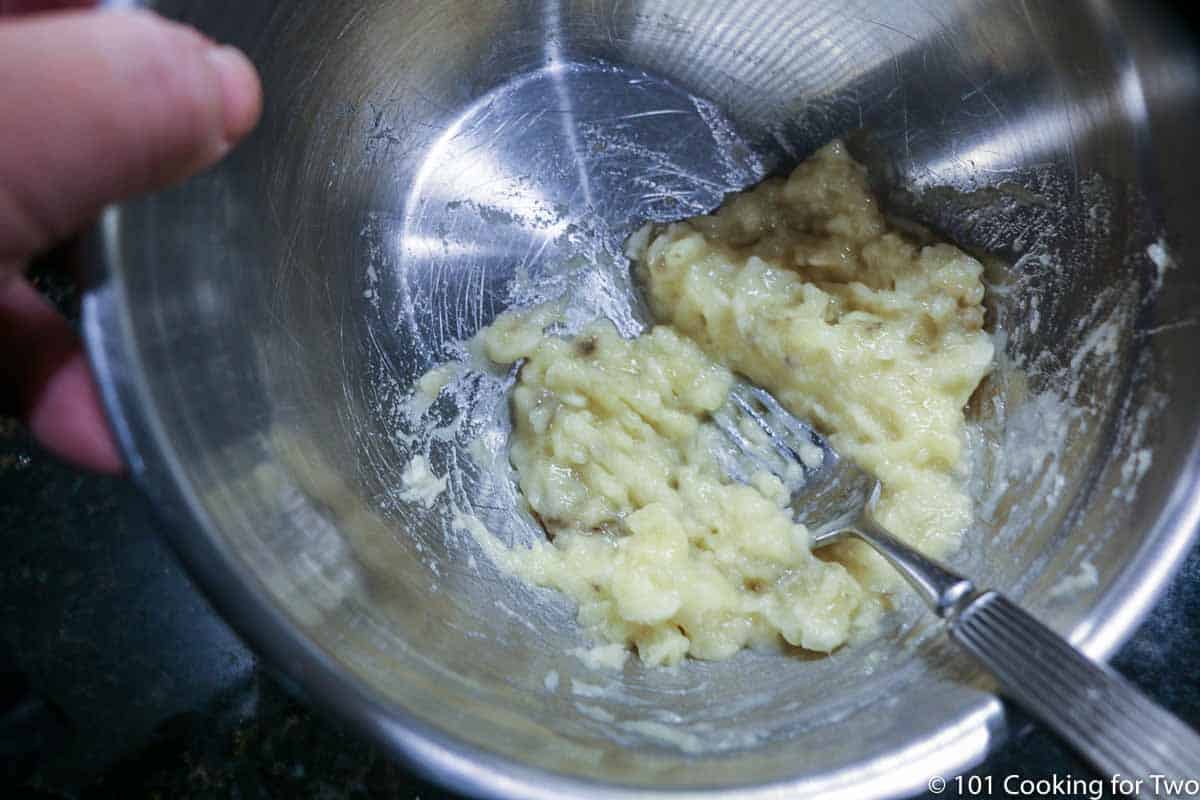 mashing a banana in bowl with fork