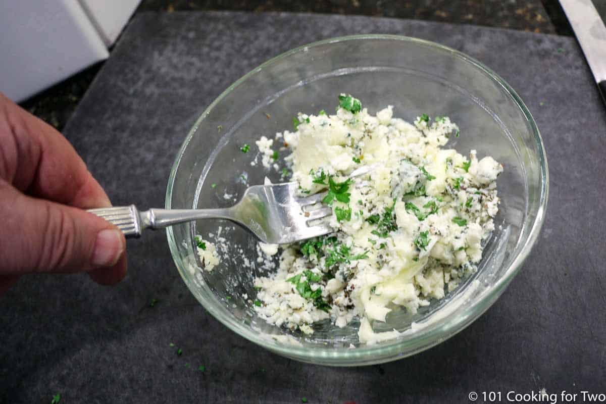 mixing compound butter in small bowl with fork.