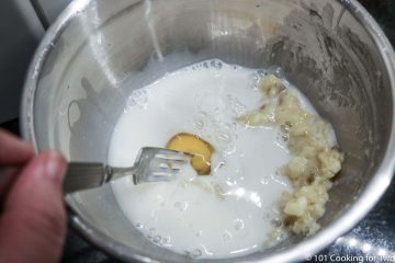 mixing milk and egg into the mashed banana in a bowl