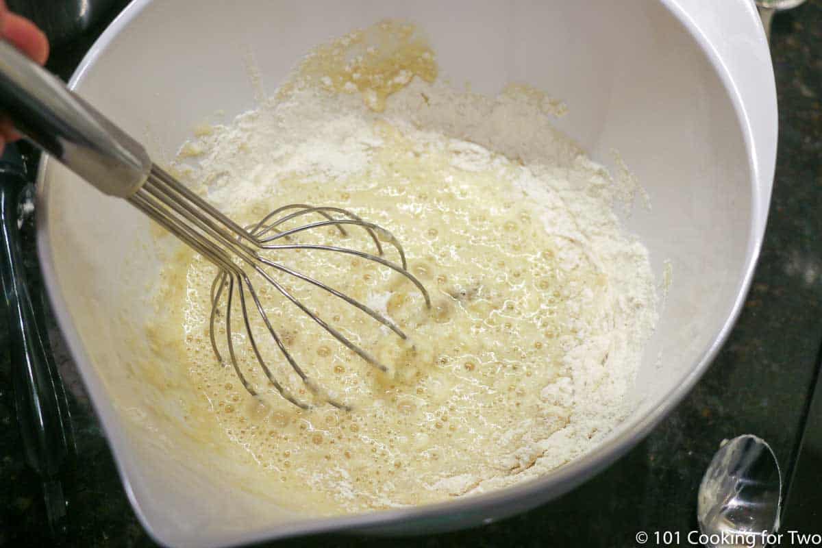 mixing wet ingredients into dry with a whisk.