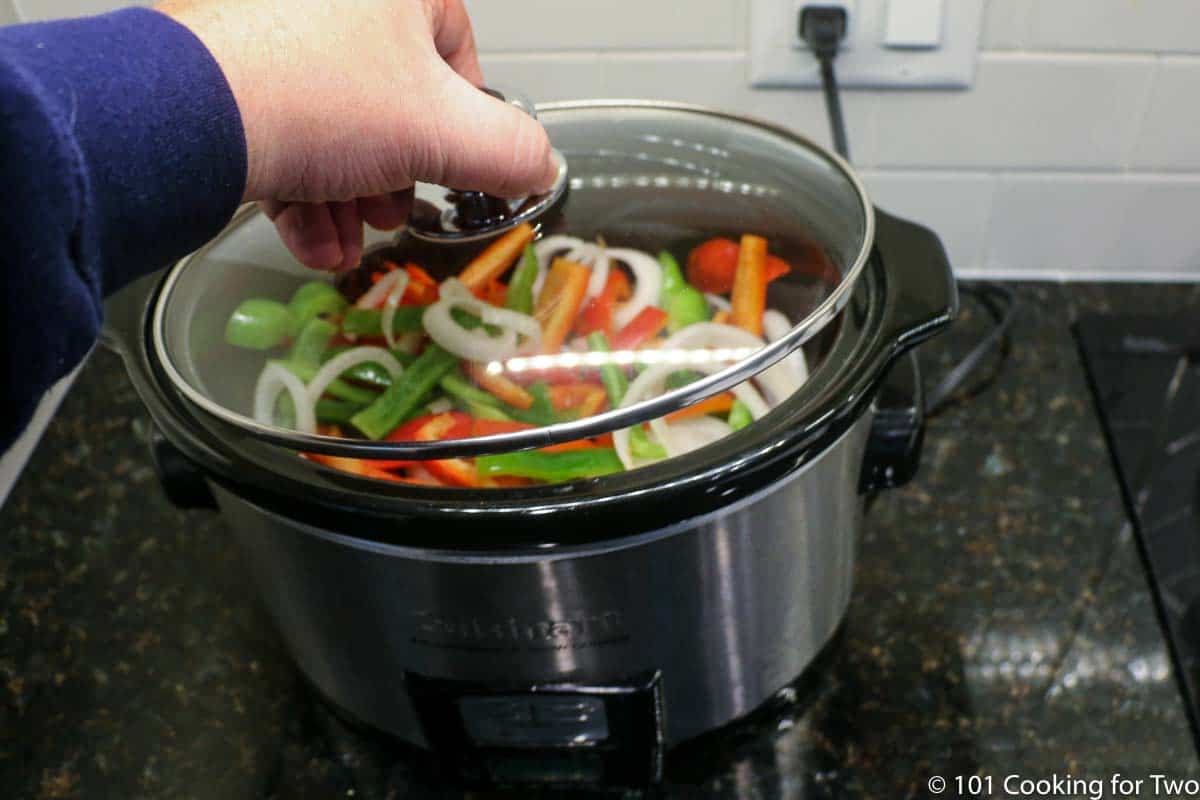 placing lid on crock pot with ingredients present