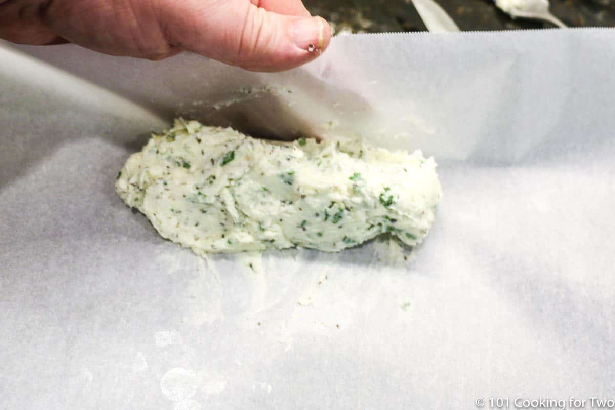 rolling a log of compound butter in parchment paper.