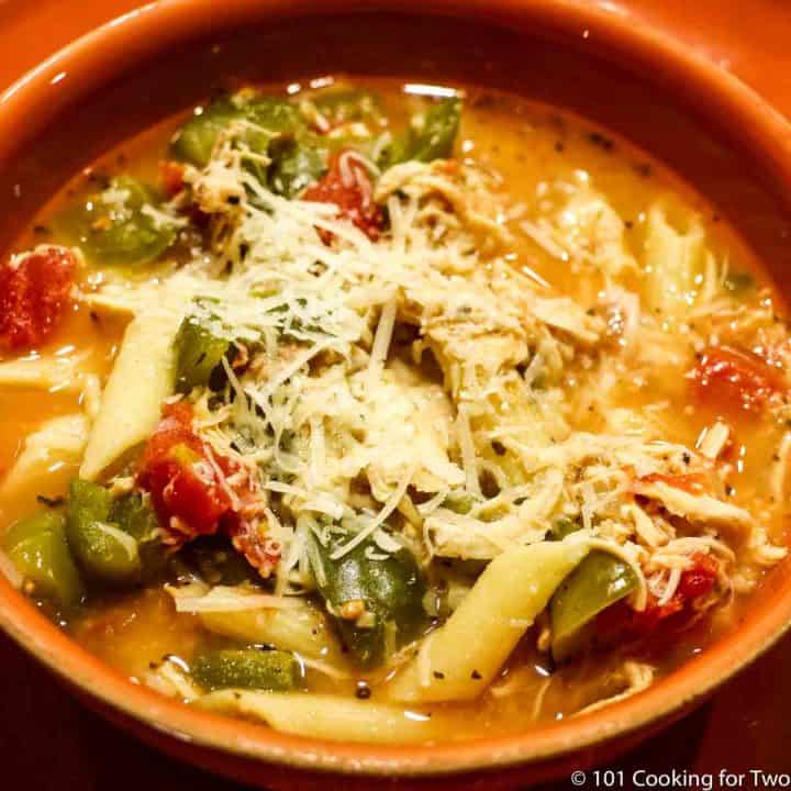 soup in orange bowl with pasta and parmesan cheese