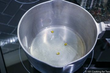 three kernals of corn in a pan with oil