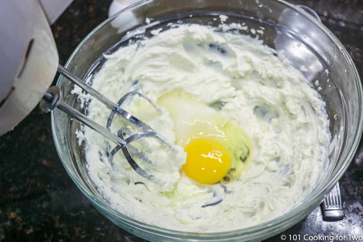 using an electric mixer to beat egg into mixture