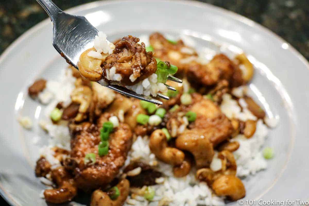 Cashew Chicken on a fork over a gray plate