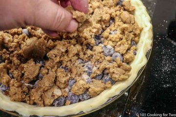 adding crumble topping to pie