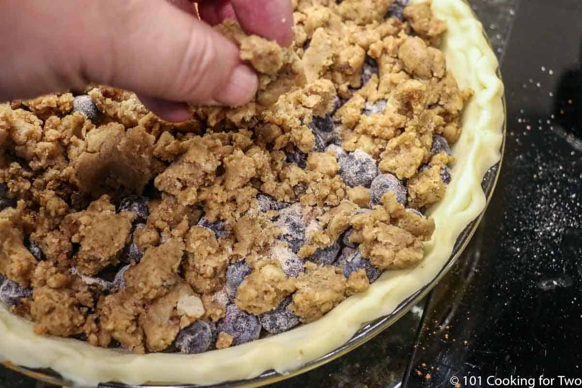 adding crumble topping to pie.