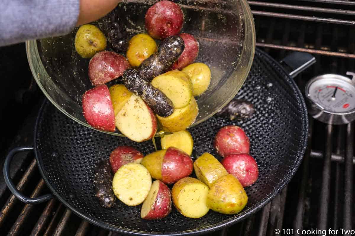 adding potatoes to grill pan over direct heat