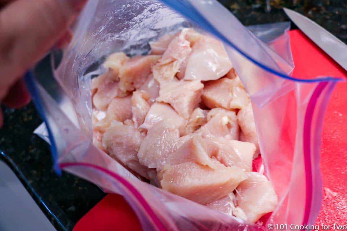 adding trimmed chicken to ziplock bag.