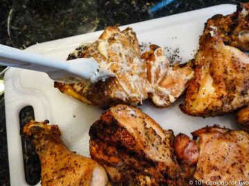 brushing white BBQ sauce on cooked chicken