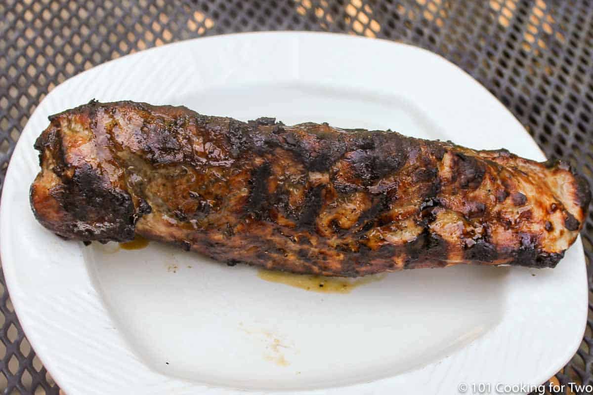 Cooked pork tenderloin on white plate.