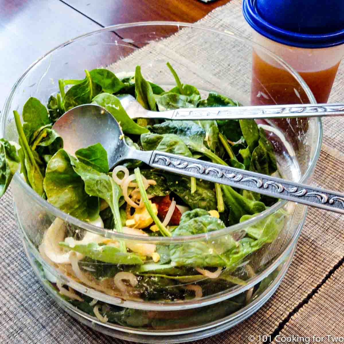 bowl of spinach salad with dressing in shaker