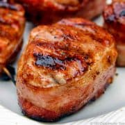 grilled bacon wrapped pork medaion on white plate