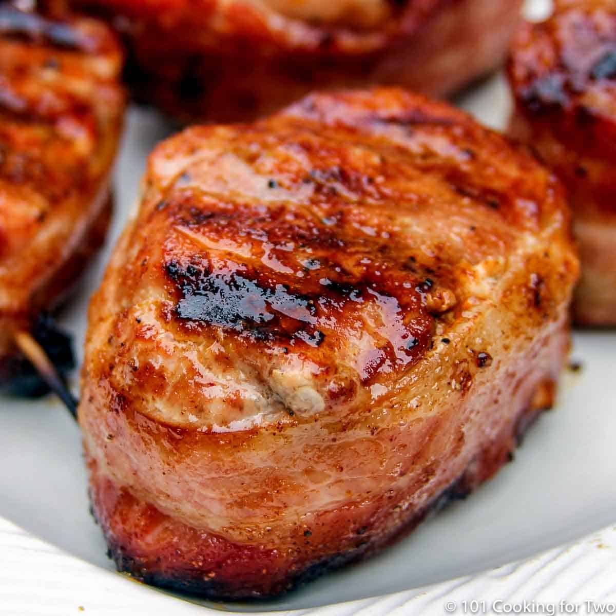 grilled bacon wrapped pork medaion on white plate