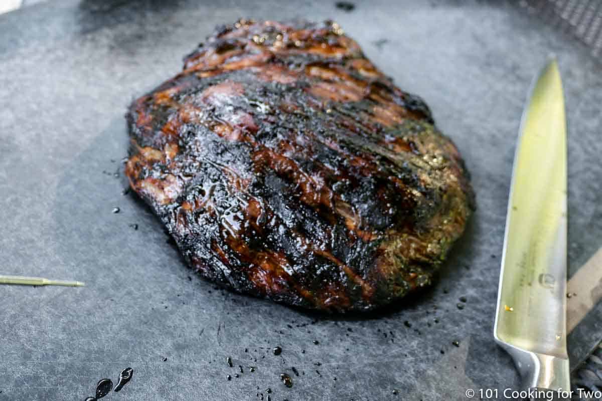 grilled flank steak on black board.