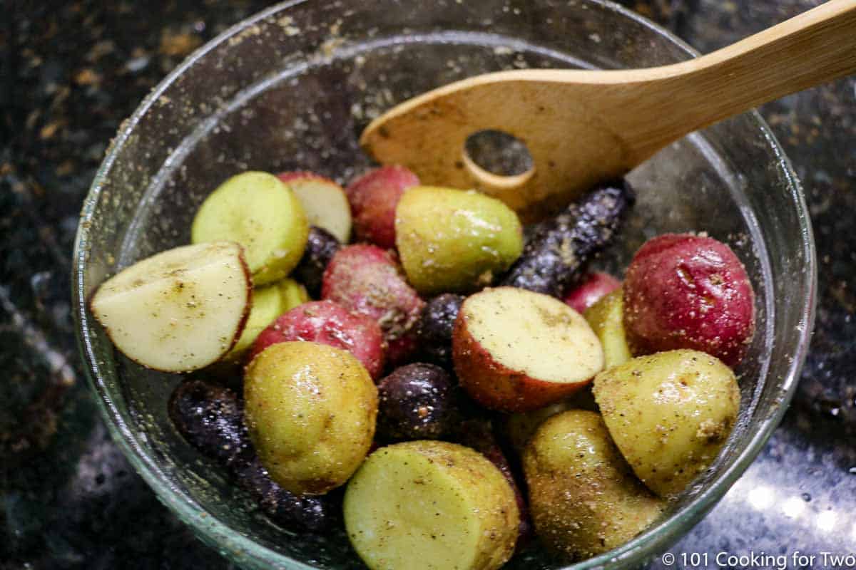 mixing potatoes with oil and seaoning in bowl.